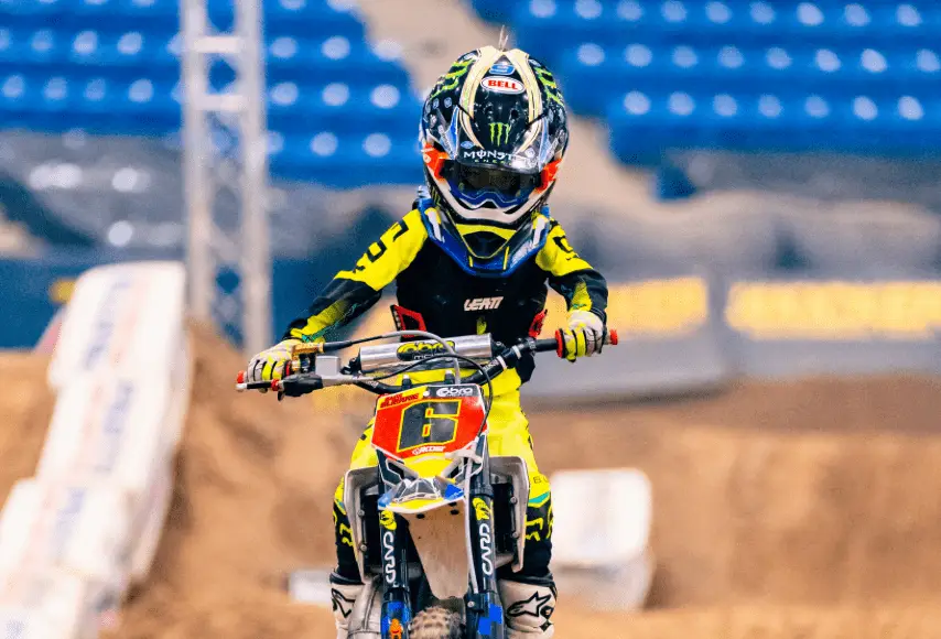 A young child riding a dirt bike at an AMA Arenacross race.